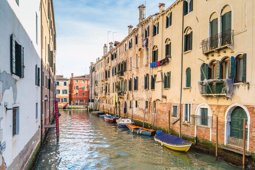 View typical canal Venice with boats mooring near ancient buildings capturing channel waterway historic architecture traditional Venetian tourism water scenic Veneto.