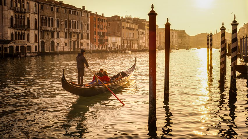 This ethereal photograph captures the romantic enchantment of Venice during golden hour through luminous color palette emphasizing warm amber and ochre tones suffused throughout the composition creating dreamlike atmospheric quality.